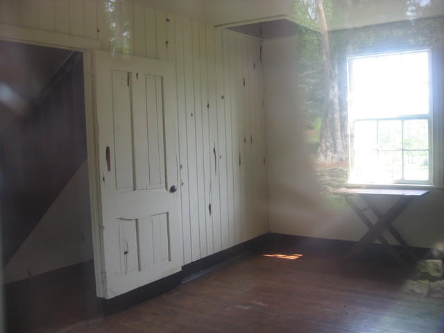 inside of house along stone wall with bullet holes. Taken through window.